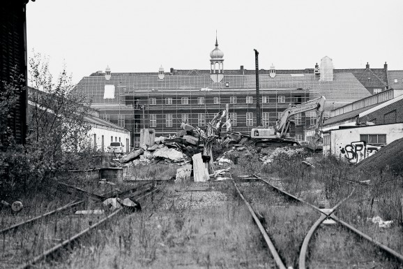 Området</br>Hovedbygningen afgrænser godsbaneområdet ud mod Skovgaardsgade, og mod vest ligger nært forbundet de tidligere varehuse, nu nordhallen og sydhallen med Ringgadebroen i horisonten. Derimellem er et stort sporområde med tilgrænsende bygninger, der tidligere også hørte sammen med Godsbanegårdens funktioner.